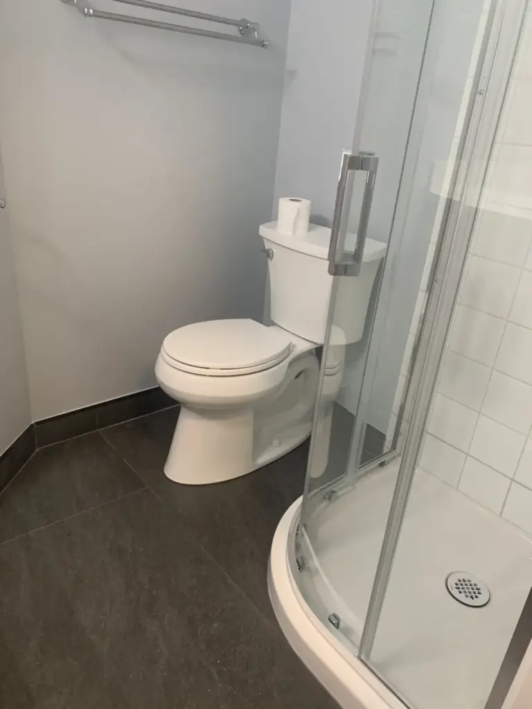 Toilet and corner shower with new floor tile, lower bathroom renovation in Surrey