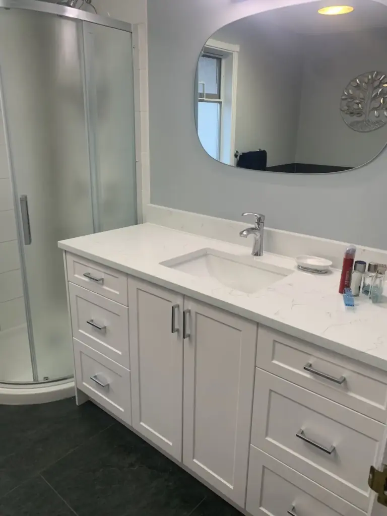 White shaker vanity with a stone countertop and oval mirror, bathroom renovation in Surrey