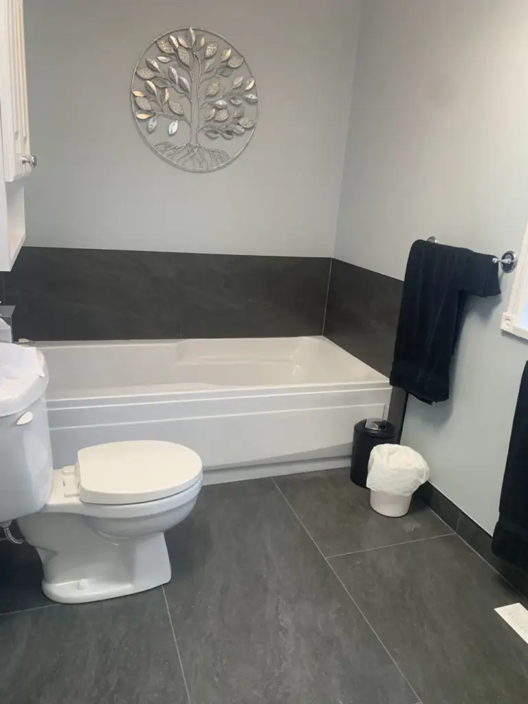Soaker tub with a dark tile surround and toilet, bathroom renovation in Surrey