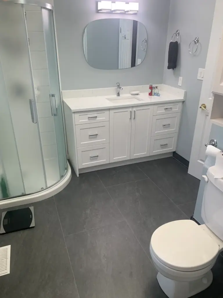 Curved glass shower and vanity with large-format floor tile, bathroom renovation in Surrey