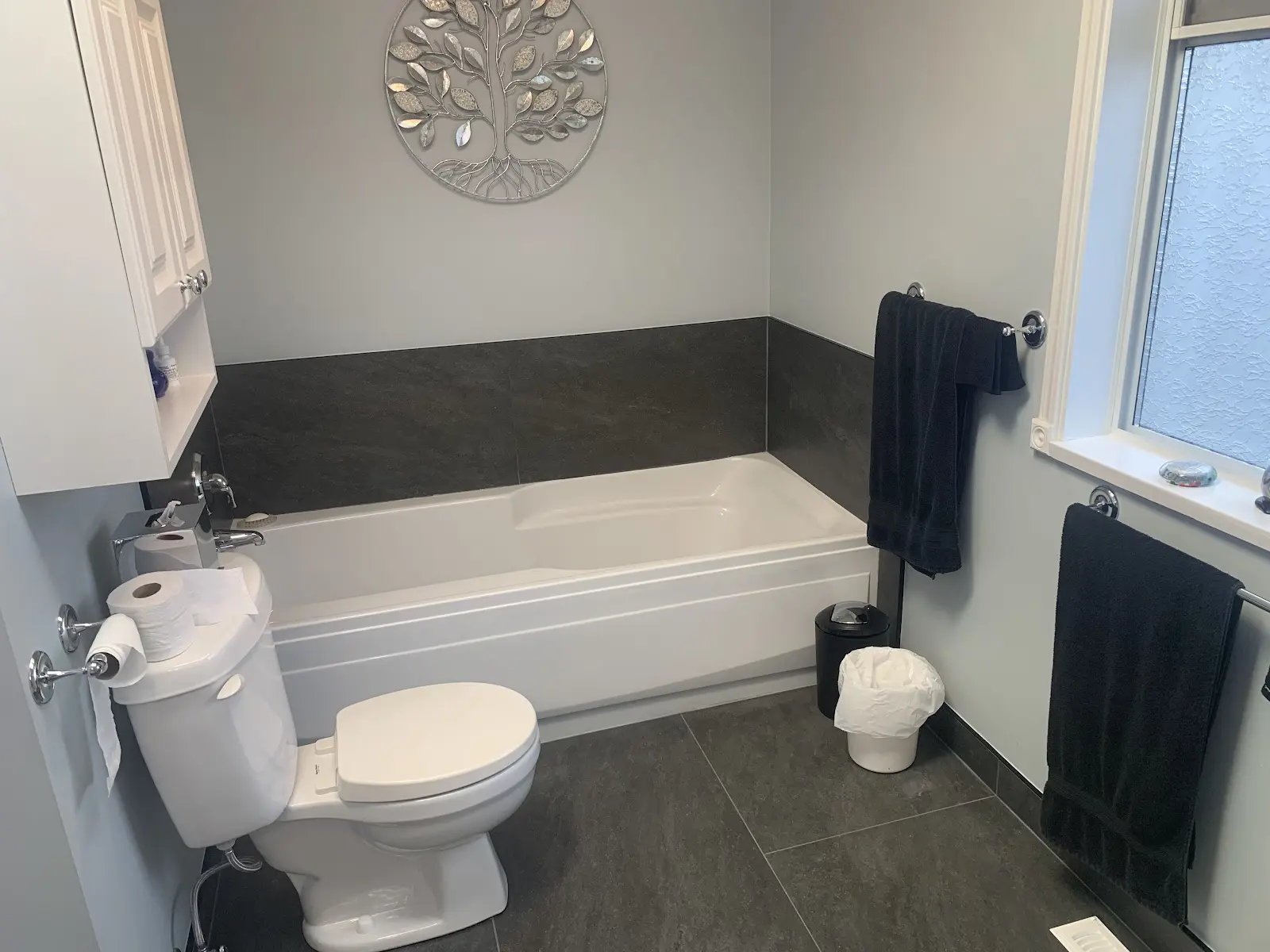 Soaker tub under a window with a dark tile surround, bathroom renovation in Surrey